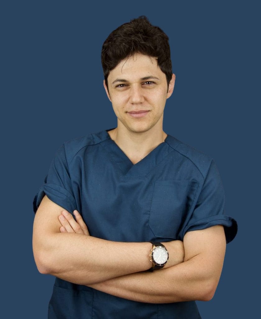 Dentista joven con uniforme azul marino y los brazos cruzados sobre fondo azul