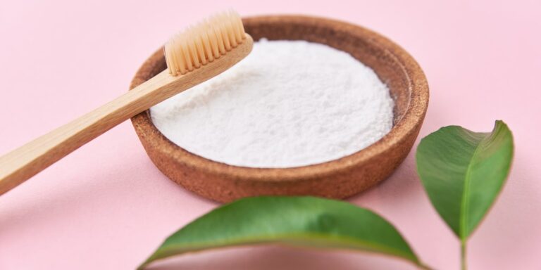 Bicarbonato para los dientes: cuenco con bicarbonato en polvo y un cepillo de dientes de bambú