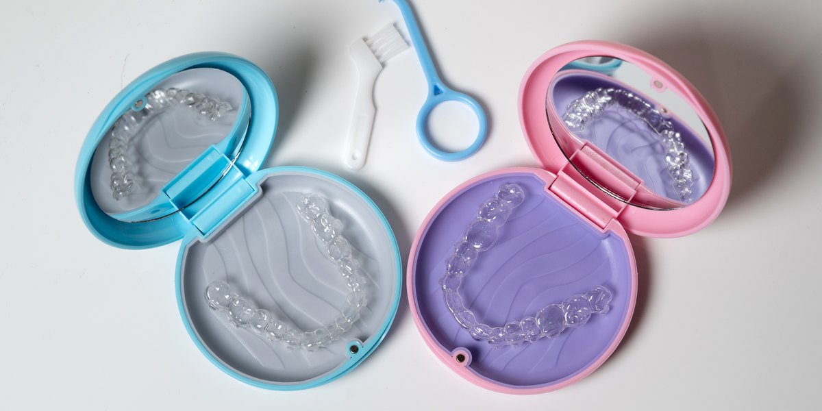 Cómo limpiar la férula dental: dos pares de férulas transparentes en sus estuches con un cepillo pequeño