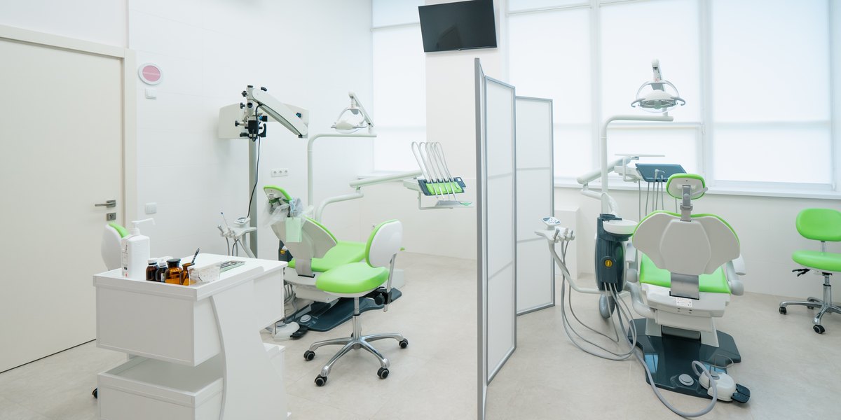Miedo al dentista: consulta dental luminosa con dos sillones vacíos separados por un biombo junto a los ventanales