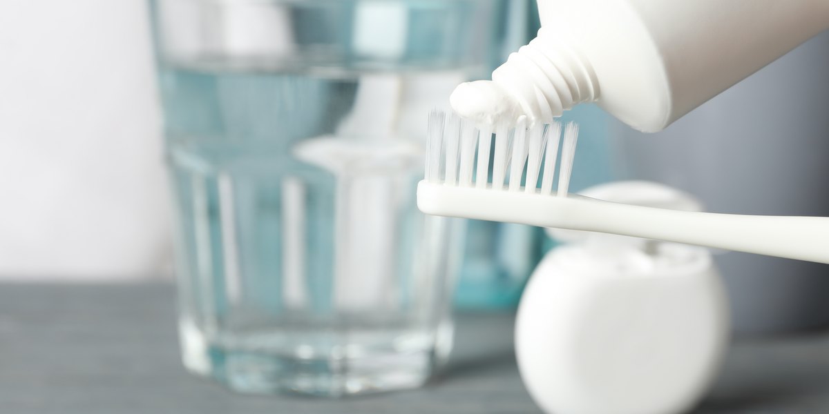 Cepillo de dientes con pasta de dientes sobre fondo con herramientas de cuidado dental, de cerca