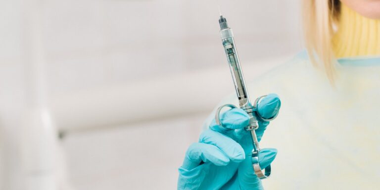 Anestesia dental: el dentista sostiene en alto, con la mano enguantada, la jeringa de anestesia